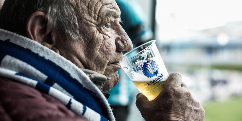 Man drinkt pintje tijdens voetbalmatch in het stadium van Gent.